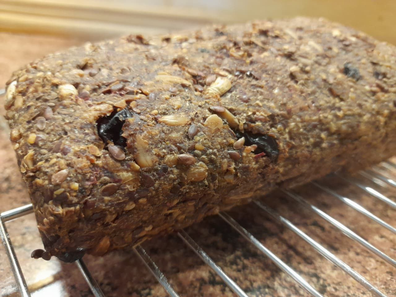Ein frisch gebackenes veganes Brot mit Rosinen und Nüssen auf einem Kühlgitter. Ballaststoffreich und lange haltbar.