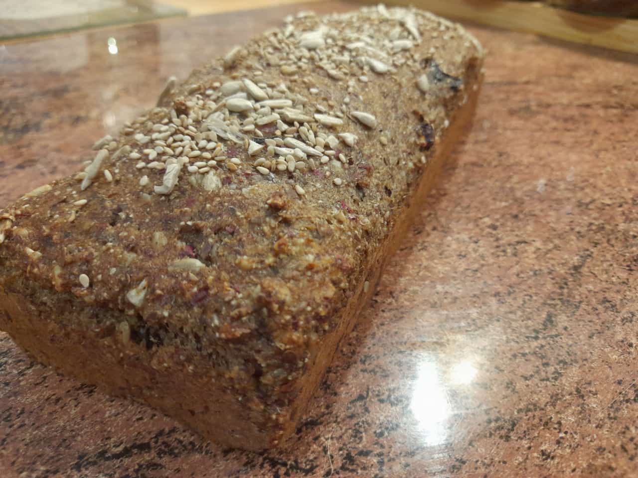 Ein frisch gebackenes veganes Brot mit Rosinen und Nüssen auf einem Backtisch. Ballaststoffreich und lange haltbar.